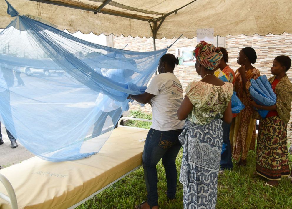 PHOTO: People show how to put a mosquito net on a bed during a free insecticide-treated mosquito nets distribution, April 24, 2015, in Abidjan, Ivory Coast.